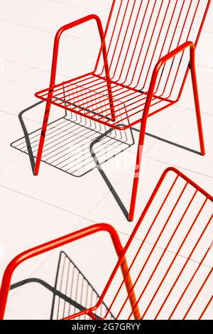 Summer outdoor red metal chairs placed on white floor in sunlight with shadow Stock Photo