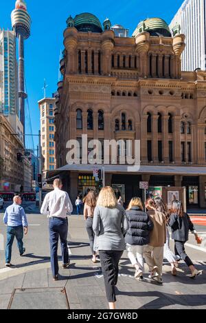 Heading in the direction of the Queen Victoria Building (QVB) and Sydney Tower, people on their lunch break cross York Street at the traffic lights Stock Photo