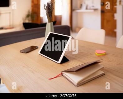 Modern tablet with black screen placed on table with smartphone and notepad at home Stock Photo