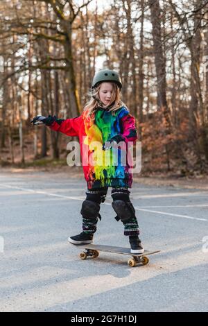 Energetic teenage girl in protective gear riding above ground with skateboard Stock Photo
