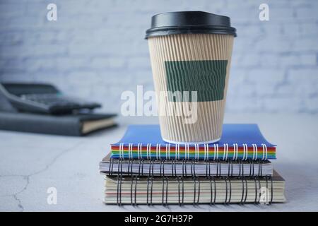 take away paper cup on stack of notepad on table  Stock Photo