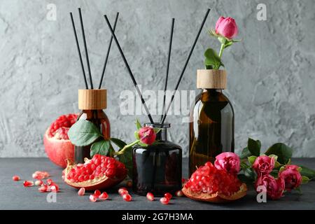 Diffusers, flowers and pomegranate on dark wooden table Stock Photo