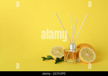 Diffuser, lemons and leaves on yellow background Stock Photo