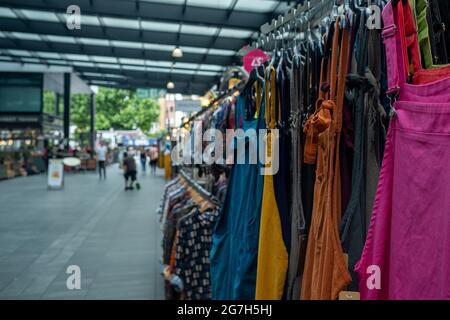 London- July, 2021: Colourful clothes for sale inside Spitalfields market in East London Stock Photo