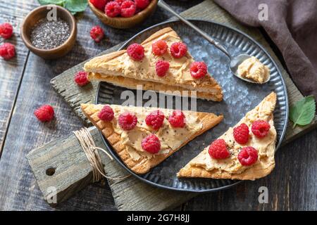 Summer sweet dessert sandwich breakfast. Tasty toasted with peanut butter and raspberry on a rustic wooden table. Stock Photo
