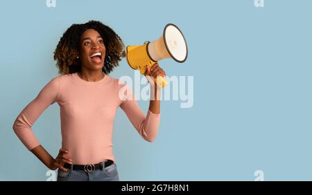 Portrait Of Joyful Black Female With Megaphone In Hands Making Announcement, Cheerful African Lady Holding Loudspeaker, Sharing News Or Interesting Of Stock Photo