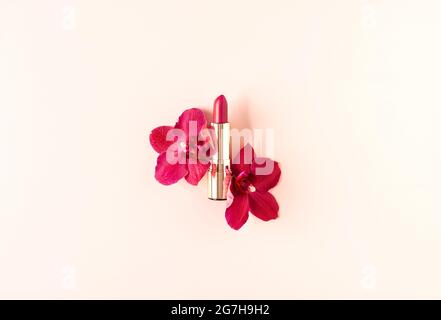 Decorative cosmetics composition of lipstick decorated with orchid flowers on pastel pink background. Natural cosmetics concept. Mockup for your desig Stock Photo