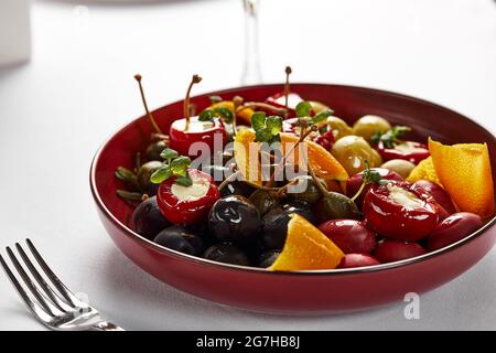 Pickled vegetables in a plate, olives, black olives, stuffed peppers, radishes. Assorted vegetables, vegetables with spices in oil close-up. Stock Photo