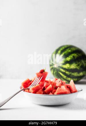 Bowl of organic watermelon pieces with wild strawberries for healthy eating on kitchen table. Copy space. Stock Photo