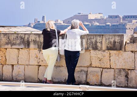 Rearview of two elderly women admire views of Valletta skyline from Manoel Island side in Gzira: Manoel Island, Gzira, Malta - March 24, 2019 Stock Photo