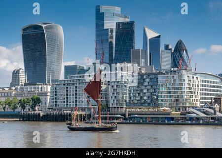 Restored Thames Sailing Barge Ardwina passing in front of the City of London financial district on its way to Tower Bridge on a July morning Stock Photo