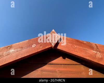 Apex of red shed roof agains blue sky Stock Photo