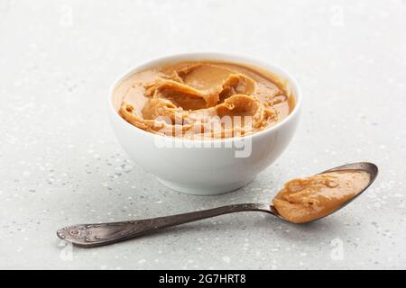 smooth peanut butter in bowl on gray background Stock Photo