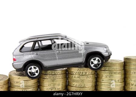 A new car on a rising stack of coins, above which is an isolated white background. Stock Photo