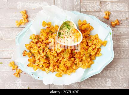 Spicy farfalle pasta chips with homemade herb dip Stock Photo