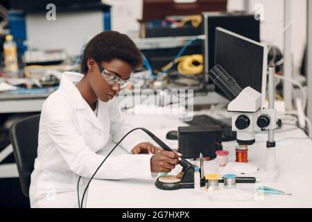Scientist african american woman working in laboratory with soldering iron Stock Photo