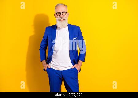 Photo portrait of confident man wearing blue suit glasses smiling happy isolated bright yellow color background Stock Photo