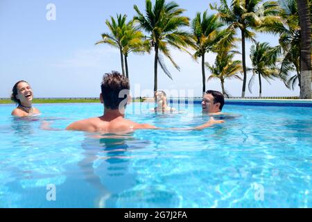 Young group of friends having a great time in the swimming pool by the beach Stock Photo