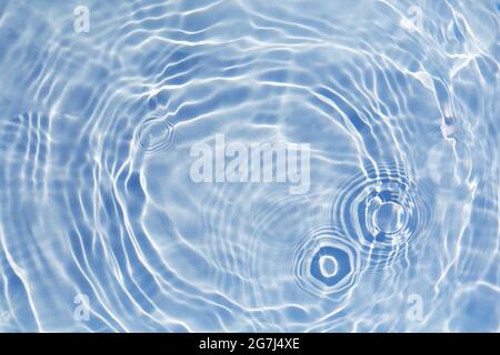 Blue clear water surface texture with splashes and bubbles. Trendy abstract water background. Water waves in sunlight. Stock Photo