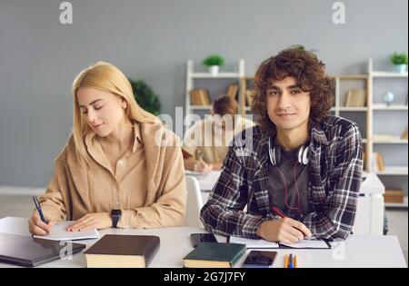 Diligent male student looking at camera sitting at desk in classroom portrait Stock Photo