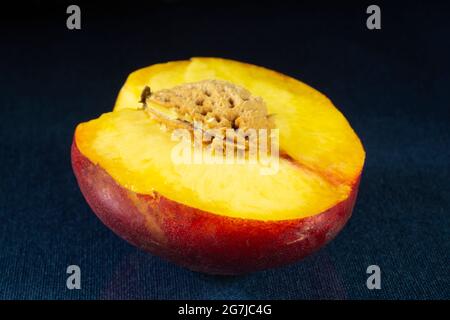 Sliced peach with a nut on the table with a reflection. Food products on a black background Stock Photo