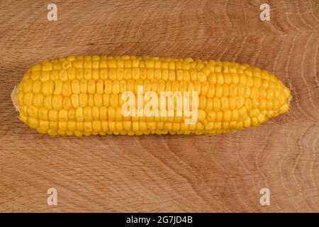 Ripe corn in a roach peeled from husk on a wooden board Stock Photo