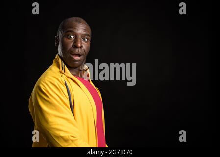 Side view of an African American man standing looking at camera black background Stock Photo