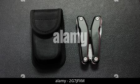 Multitool with a black case on a black leather background Stock Photo