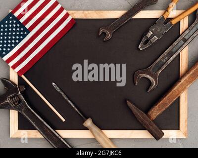 LABOR DAY. Hand tools and the Flag of the United States of America lying on the table. View from above, close-up. Congratulations to family, relatives Stock Photo