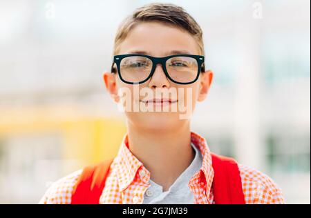 Portrait of a cute boy in glasses who is going to school with his school backpack, Student boy on the way to school, Learning for children Stock Photo