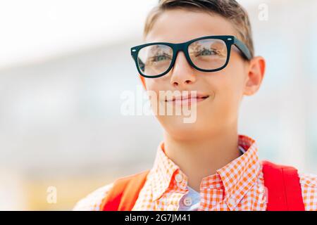 Portrait of a cute boy in glasses who is going to school with his school backpack, Student boy on the way to school, Learning for children Stock Photo