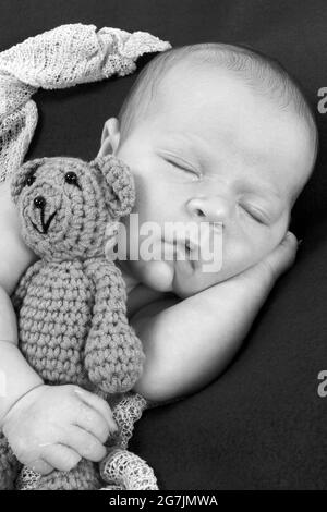 newborn baby boy  asleep on a blanket cuddling a teddy Stock Photo