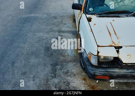 Abandoned and rusted old car parked on a cement floor. Stock Photo