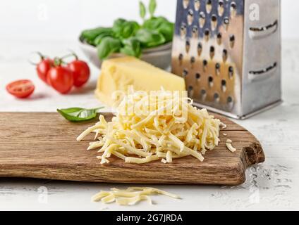 grated cheese on wooden kitchen cutting board Stock Photo
