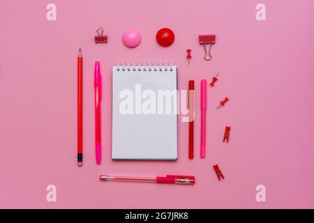 White notebook lies in the form of blank on pink background with red pen with markers. School supplies for girl in pink colors Stock Photo