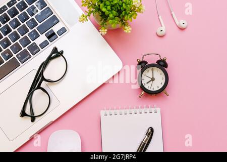 Blank white notepad with office and personal accessories, black alarm clock and glasses, on pink background, business and education motivation and inspiration concept. Stock Photo
