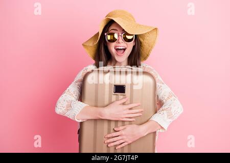 Photo of cute impressed young lady wear lace cardigan cap smiling hugging suitcase isolated pink color background Stock Photo