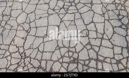 Top view of an old asphalt road in wet cracks. Stock Photo