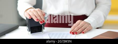 Businesswoman puts stamp on documents on work table Stock Photo