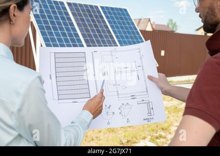 Head engineer and investor discussing construction plan of building with solar panels Stock Photo