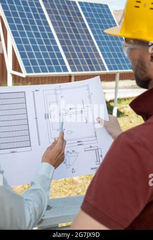 Head engineer and contractor discussing construction plan of house roof with solar panels Stock Photo