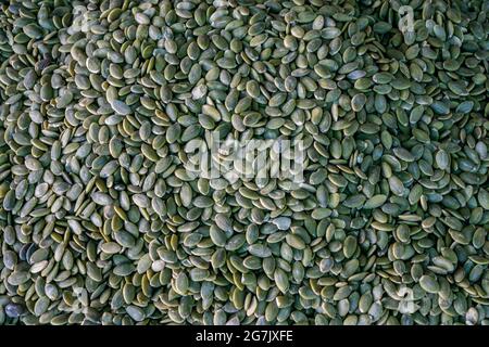 A pile of peeled pumpkin seeds, a stand with pumpkin seeds in close-up at the farmer's market. Copy space. Stock Photo