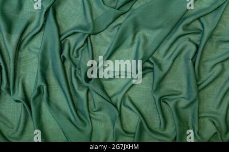 Abstract background from a beautiful green fabric draped with soft folds. Elegant template or patter with copy space for design. Recycled eco textiles Stock Photo