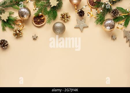 Christmas and New Year holiday background. Christmas tree branches, balls and spiral serpentine on yellow background. Top view, flat lay, copy space. Stock Photo