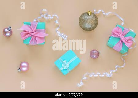 Light blue present boxes with bow on beige background with balls and boubles. Christmas concept. Top view, flat lay. Stock Photo
