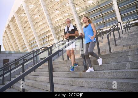 Attractive sportive middle aged couple, man and woman in sportswear training together outdoors Stock Photo