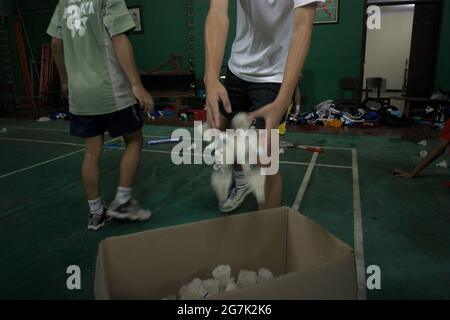 Young badminton athletes collecting shuttlecocks, put them together in a box after a training session at Jaya Raya badminton club in Jakarta, Indonesia. Stock Photo