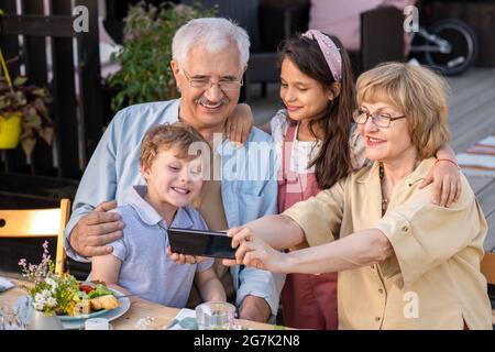 Happy grandparents and grandchildren taking selfie together at family reunion Stock Photo