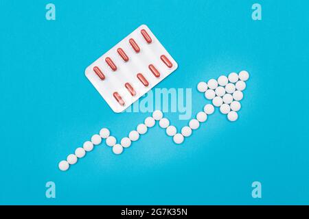 Global Pharmaceutical Industry and Medicinal Products - Upward Arrow Made from White Pills on Blue Background Stock Photo