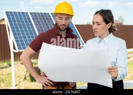 Project manager and contractor discussing maintenance of solar panels, green energy concept Stock Photo